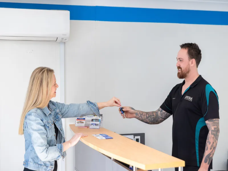 Dylan the mechanic at PPM taken keys from a female customer at the reception desk